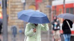 Regenschirm - Regen - Wind - Frau - Öffentlichkeit